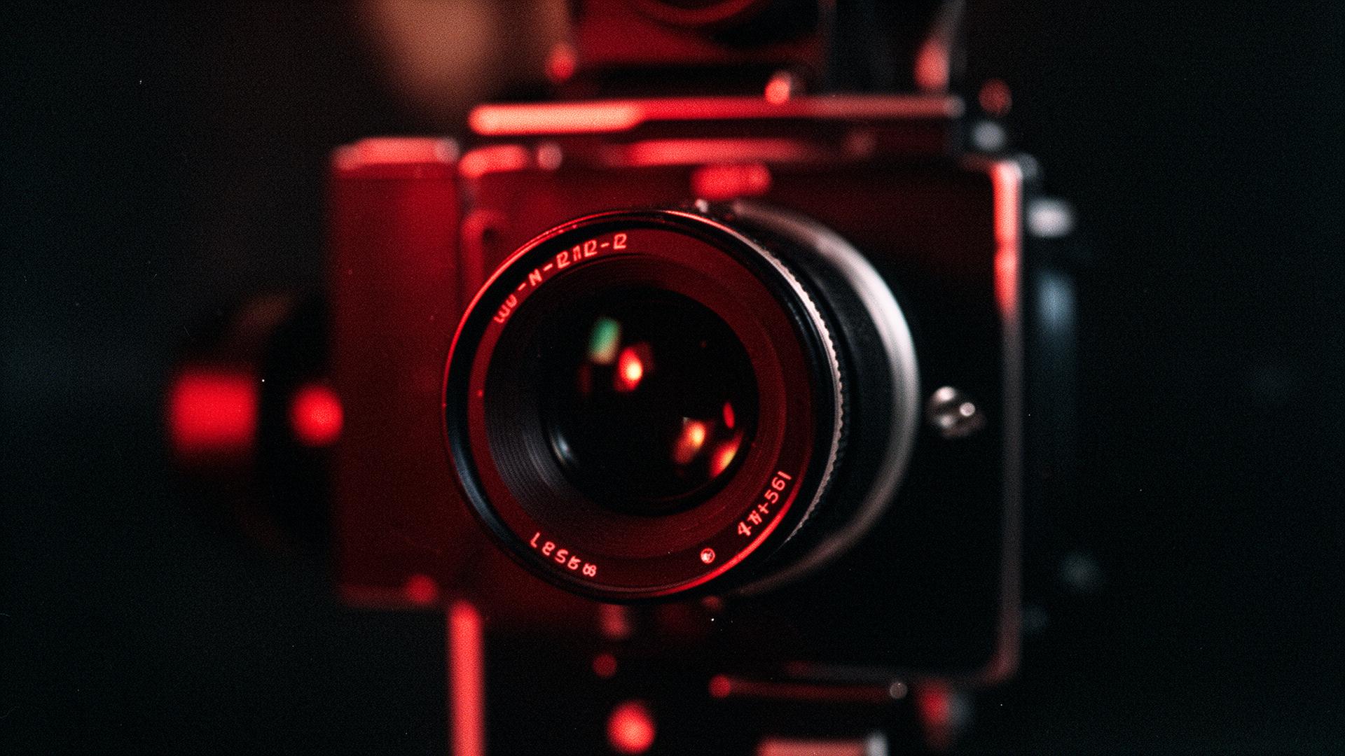 Close-up of a cinema camera lens lit with red neon